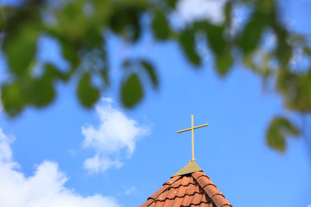 Die Spitze des Kirchturmes mit einem goldenen Kreuz.